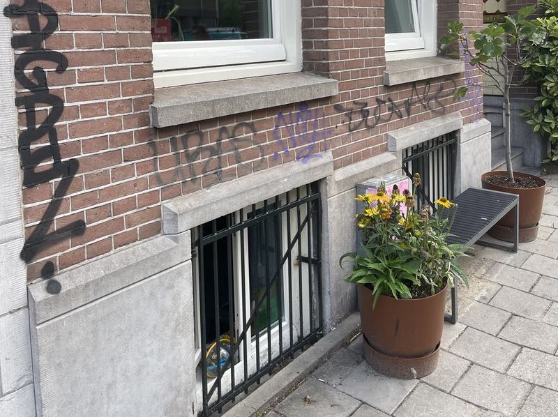 Gevel met zwarte en paarse graffiti tags voor reiniging in De Pijp, Amsterdam