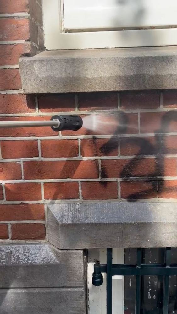 Graffiti van een bakstenen gevel verwijderen met de hogedrukreiniger in Amsterdam